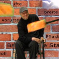 Ein Rollstuhlfahrer mit schmerzverzerrtem Gesicht. Ein orangefarbener Hammer schlägt ihn. Im Hintergrund eine Mauer.