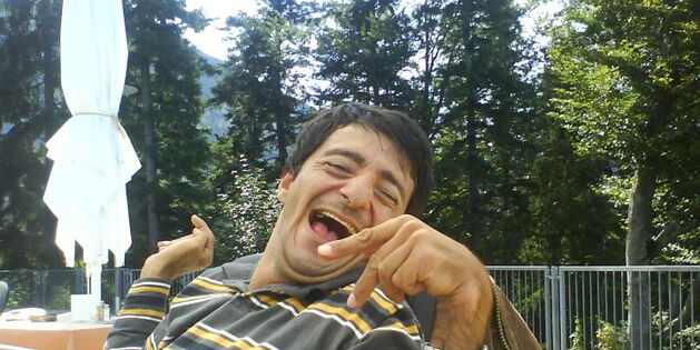 Süleyman Kurt hat gut lachen! Auf der Aussichtsterrasse beim Karren in Dornbirn. Im Hintergrund Wald, im Vordergrund das strahlende Lachen von Sülo.