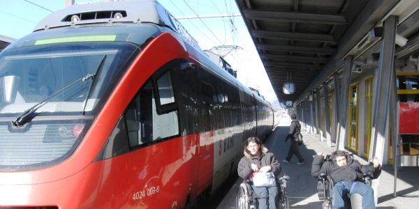 Ein Niederflurzug am Bahnsteig 1 in Bludenz. Claudia Fessler und Sueleyman Kurt warten in ihren Elektrorollstühlen auf dem Bahnsteig auf den Einstieg.