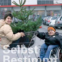 Selbst – Bestimmt – Leben / Wege zur SelbsterMÄCHTigung von Menschen mit Behinderungen || Eine Frau sitzt mit einem Tannenbaum im Einkaufswagen und ein Rollstuhlfahrer schiebt den Wagen.