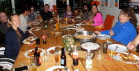 Leute sitzen rund um einer gedeckten Tafel mit leckeren Speisen