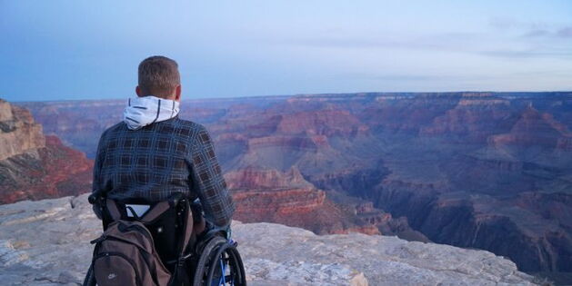 Ein Rollstuhlfahrer steht auf einem Felsplateau mit weitem Blick auf den Grand Canyon. Fotoquelle: www.freeonwheels.de