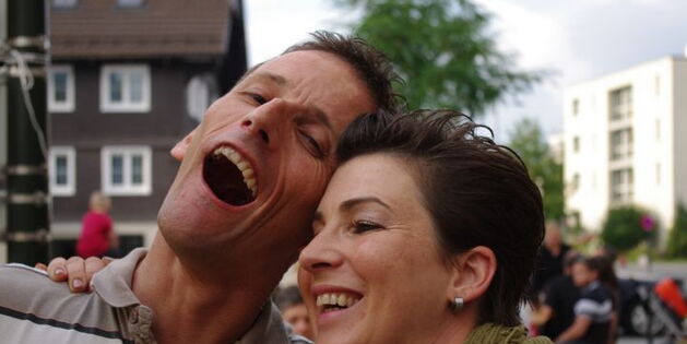 Ein Mann und eine Frau, hell lachend, mit offenen Mündern.