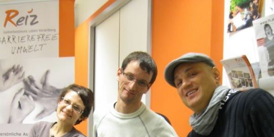 Angela Kreil, Andreas Guth und Reinhard Zischg lachen in die Kamera. Bunter Hintergrund mit Reiz-Orange Farbe und das Reiz-Banner.