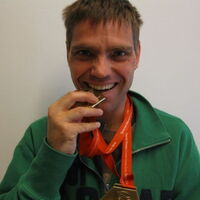 Thomas Wachter prüft den Goldgehalt seiner Siegmedaille und beißt hinein.