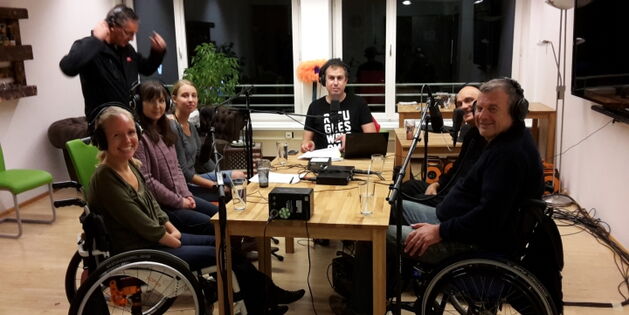 Diskussionsrunde der Livesendung FM4 Auf Laut: drei Frauen, drei Männer sitzen um den Tisch mit Kopfhörern um die Ohren, Mikrophonen vor den Mündern. Alle lachen in die Kamera. Der ORF Techniker im Hintergrund stehend ist mit seinem Kopfhörer beschäftigt.