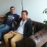 Lächelnd auf der braunen Couch von Reiz: im Vordergrund Selbsthilfe-Vorarlberg-Geschäftsführer Nikolas Burtscher; links im Bild Reiz-Obmann Andreas Guth.