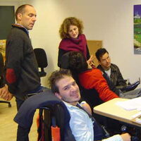 Treffpunkt - Menschen stehen um einen Schreibtisch.