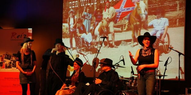 Auf der Bühne: Obmann Andreas Guth als Friedensrichter bei der Begrüßung der Ballgäste. In der Mitte Sabrina Nitz als Indianerin und Reinhard Zischg als Revolverheld. Links und Rechts  die beiden als Cowgirls verkleideten Gebärdendolmetscherinnen.