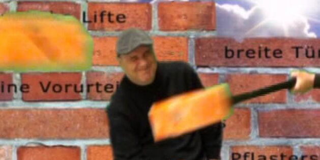 Ein Rollstuhlfahrer mit schmerzverzerrtem Gesicht. Ein orangefarbener Hammer schlägt ihn. Im Hintergrund eine Mauer.