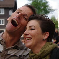 Ein Mann und eine Frau, hell lachend, mit offenen Mündern.