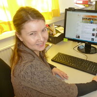 Elisabeth Ha an ihrem Arbeitsplatz. Die rechte Hand an der Maus, vor dem Bildschirm die Tastatur, auf dem Bildschirm die Reiz-Homepage. Sie dreht lächelnd ihren Kopf über die Schulter zum Fotograf.