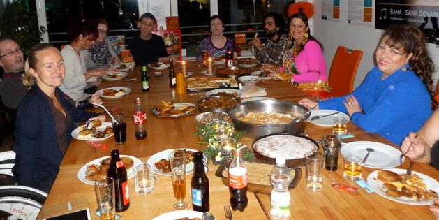 Leute sitzen rund um einer gedeckten Tafel mit leckeren Speisen