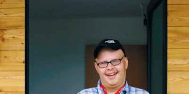 Foto: Caritas. Ein junger Mann mit Schirmmütze hält dem Betrachter stolz seine Wohnungsschlüssel entgegen.