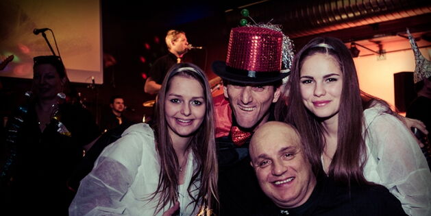 Zwei hübsche Astronautinnen in weißen Raumanzügen flankieren die schwarzgekleideten Reizler Andreas Guth und Reinhard Zischg. Andreas mit rotsilber glänzendem Magierzylinder auf dem Kopf. Im Hintergrund spielt die Band.