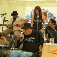 Reinhard Zischg mit Hut am Kopf, Rollstuhl am Hintern und Blues in den Knochen singt voller Kraft ins Mikrofon. Die Band C.C.Mate mit Gitarrist Mathias Zabransky, Sängerin Claudia Walla und Chris Frick begleitet ihn.