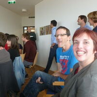 Gäste sitzen erwartungsvoll auf den Stühlen. Julia Fischbach und Andreas Guth lachen dabei freundlich in die Kamera. Im Hintergrund der Direktor der Kathi-Lampert-Schule, Gerhart Hofer.