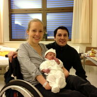 Sabrina Nitz und Daniel Studer strahlen in die Kamera. Sabrina hält ihr Baby Jamie Noel in den Armen und zeigt es dem Fotografen. Jamie ist neugierig und interessiert sich mehr für das Geschehen am Nebentisch.
