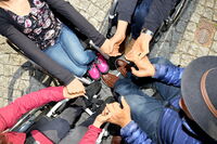 Vier RollstuhlfahrerInnen sitzen im Kreis und halten sich die Hände.