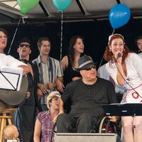 Foto: Ralph Hoppe. Die ReizlerInnen singen mit der Band C.C.Mate auf der Inklusionsbühne in München. Alle Münder offen, die Seelen am Schwingen.
