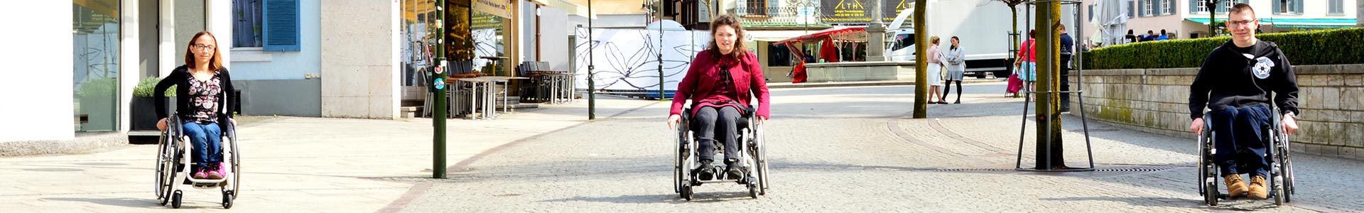 Panoramabild: Drei RollstuhlfahrerInnen fahren auf den Fotografen zu.